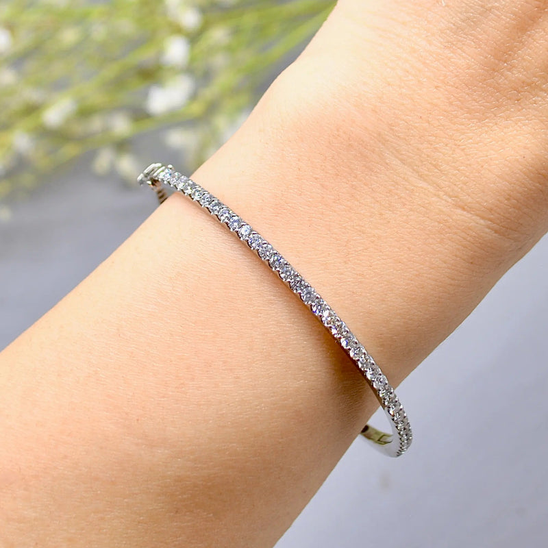 white gold bangle with clear diamonds on a blurred floral background