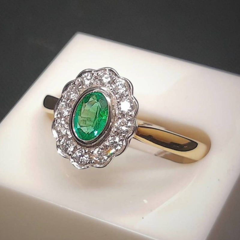 emerald and diamond daisy or halo style engagement ring